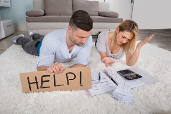 Couple lying on carpet, man holding a sign that reads help