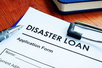 An FHA 203(h) disaster loan application with a pen on top of it.
